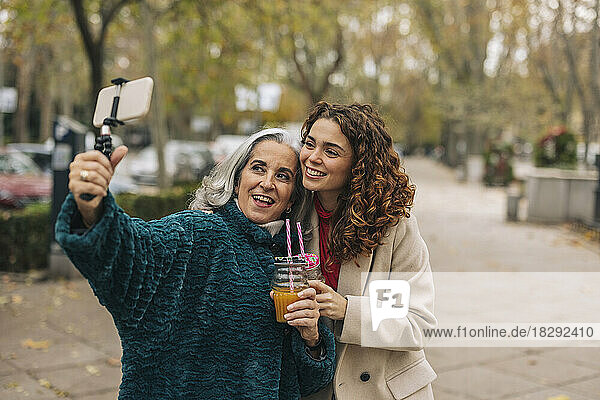 Glückliche Großmutter und Enkelin machen Selfie mit einem Glas Saft
