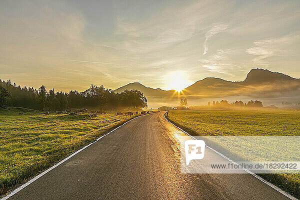 Germany  Bavaria  Jachenau  Country road at foggy sunrise