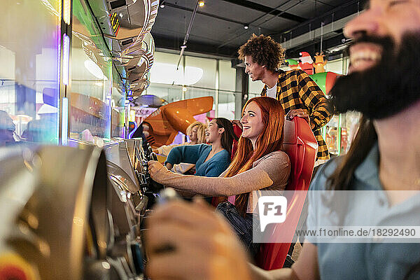 Happy young women having fun with driving simulator in arcade