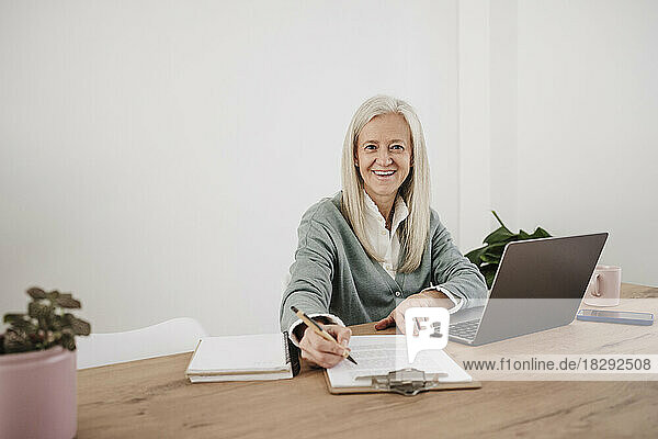 Happy freelancer with documents and laptop in home office