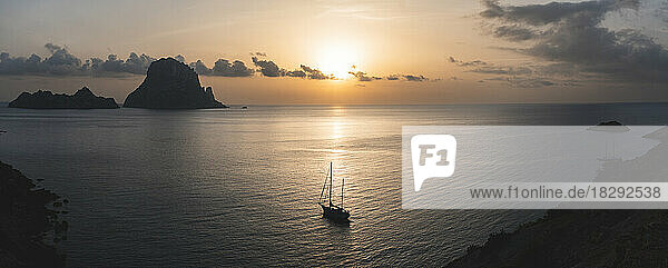 Spain  Balearic Islands  Sailboat floating near shore at sunset with Es Vedra island in background