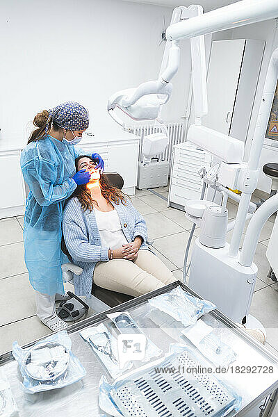 Young dentist examining patient on chair at clinic