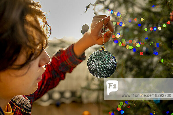 Boy decorating Christmas tree at home