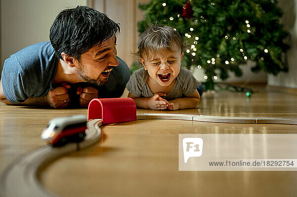 Fröhlicher Vater und Sohn spielen zu Hause mit der Spielzeugeisenbahn