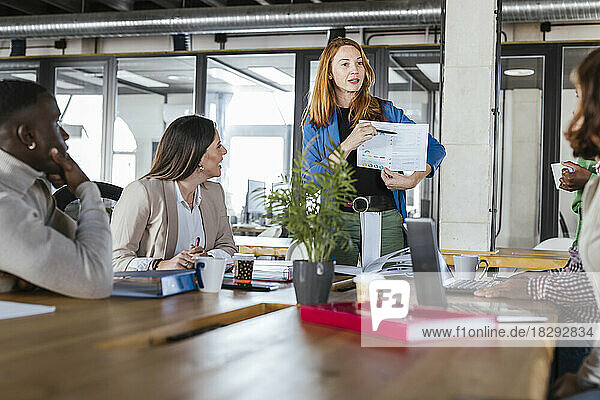 Businesswoman discussing over document with colleagues in meeting