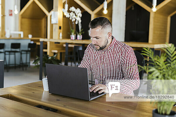 Businessman working on laptop at desk in coworking office
