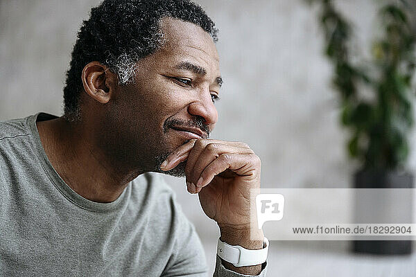 Smiling mature man with hand on chin day dreaming