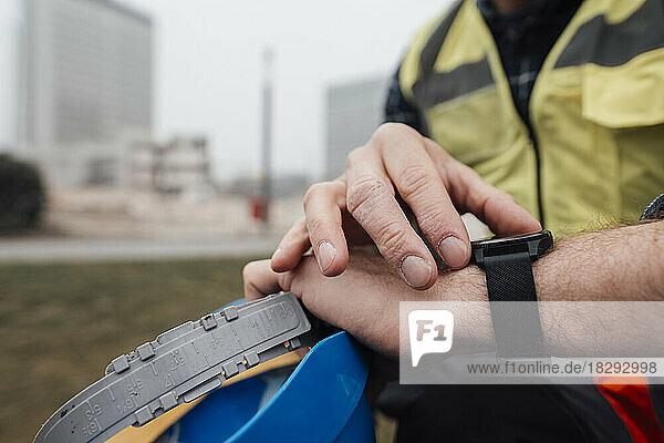 Blue-collar worker checking time at construction site