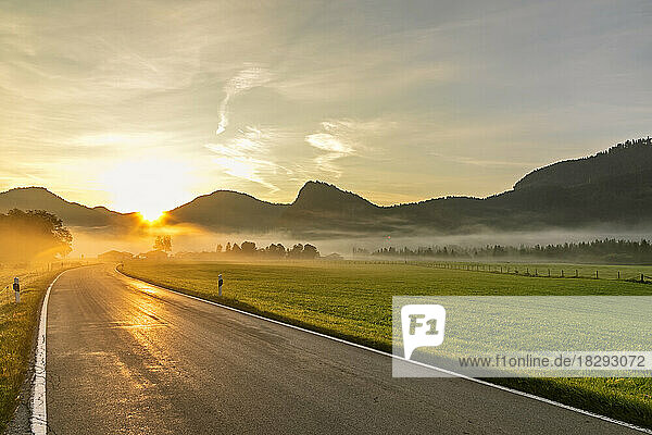Germany  Bavaria  Jachenau  Country road at foggy sunrise