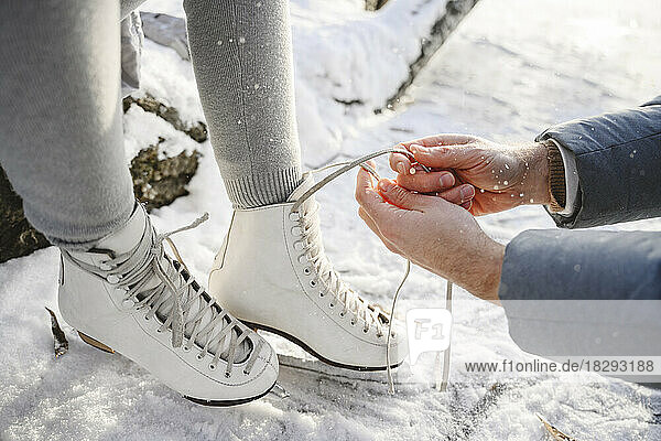 Father tying lace on daughter's ice skates