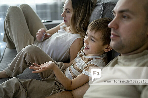 Mother and father with son watching TV at home