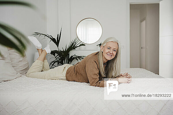 Smiling mature woman relaxing on bed at home