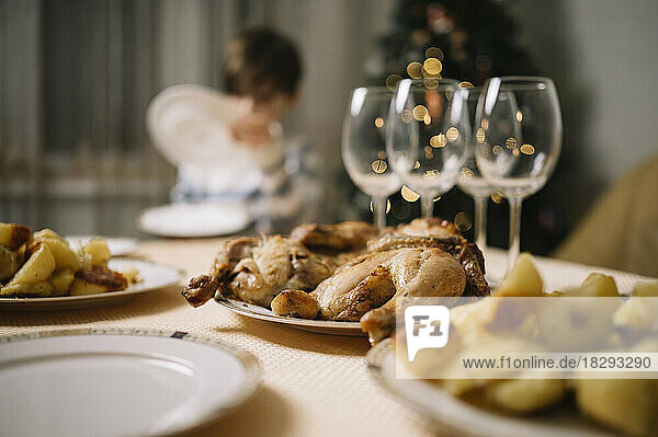 Food and wine glasses on table with boy in background