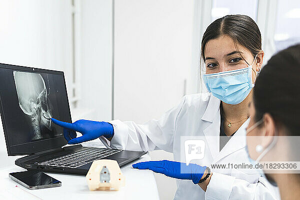 Dentists discussing over x-ray image on laptop