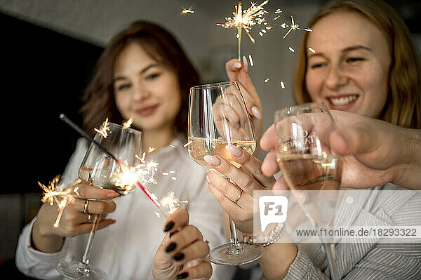 Glückliche Freunde  die zu Hause mit Gläsern Champagner und Wunderkerzen feiern