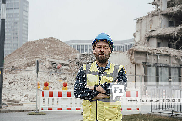 Mature worker with arms crossed standing at construction site