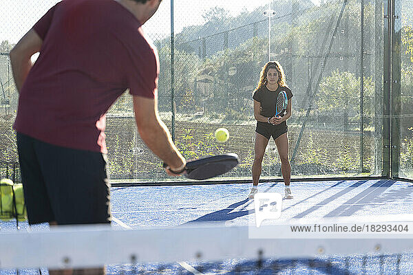 Junger Mann spielt an sonnigem Tag Paddle-Tennis mit Frau