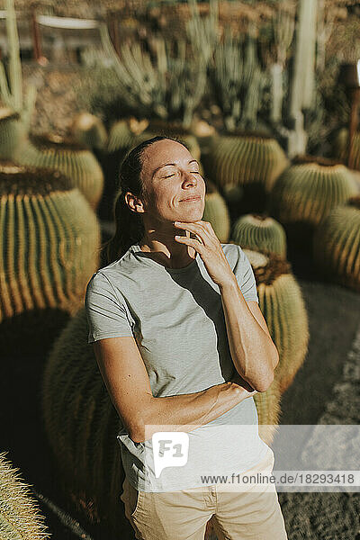 Smiling woman with eyes closed standing in cactus garden