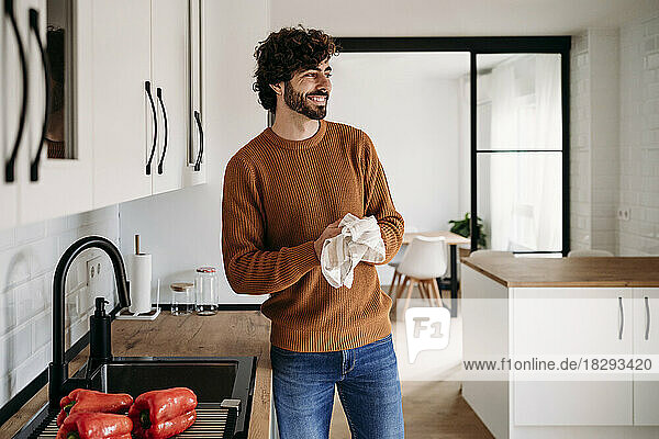 Happy man drying hands with napkin at home