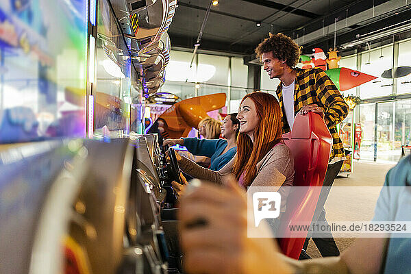 Fröhliche Freunde  die Spaß beim Spielen von Rennvideospielen in der Spielhalle haben