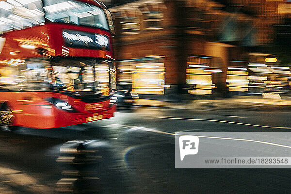 UK  England  London  Blurred motion of double-decker driving along city street at night