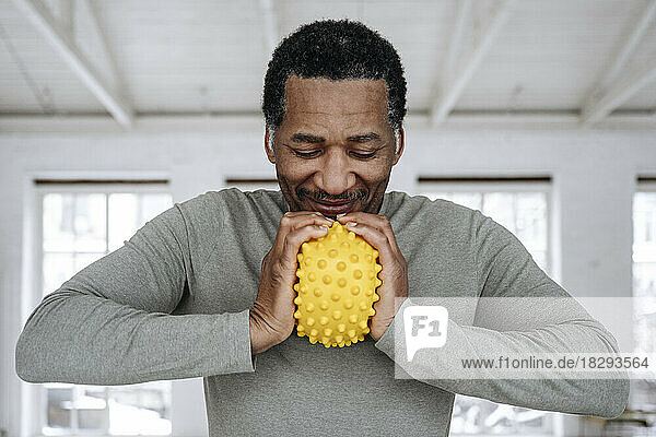 Happy man squeezing yellow stress ball at home
