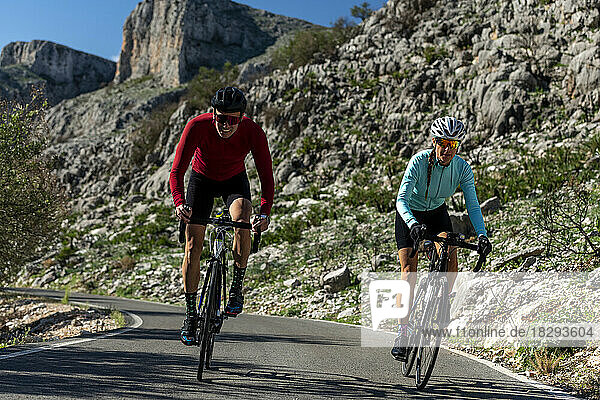 Radfahrer fahren gemeinsam mit dem Fahrrad auf der Straße vor Felsen