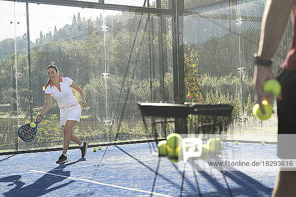 Young woman playing paddle tennis at sports court
