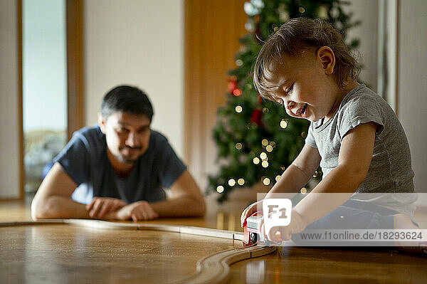 Glücklicher Sohn und Vater  die zu Hause mit der Spielzeugeisenbahn spielen