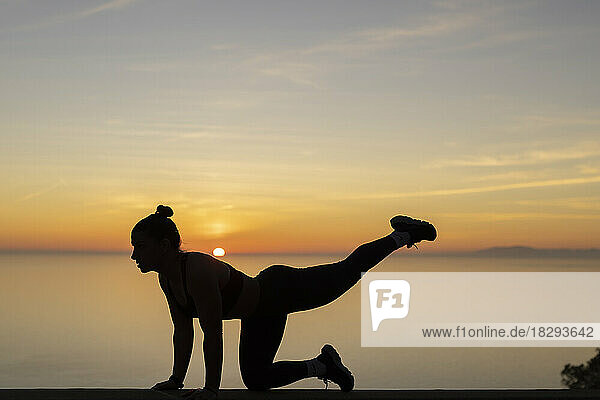 Silhouette woman practicing yoga at sunset