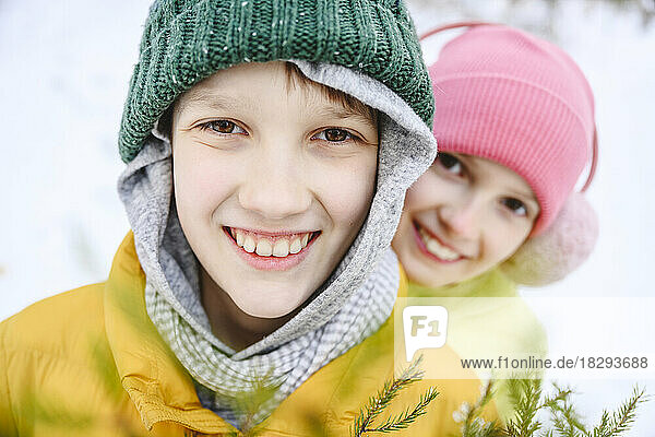 Happy brother and sister wearing knit hats in snow
