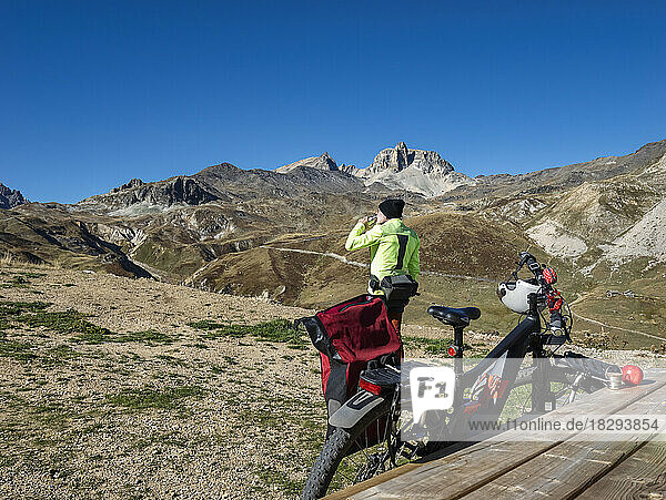 Senior man drinking water in front of mountain bike at Vanoise National Park  France