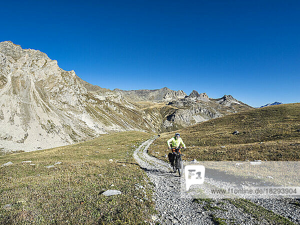 Senior man riding mountain bike on sunny day at Vanoise National Park  France