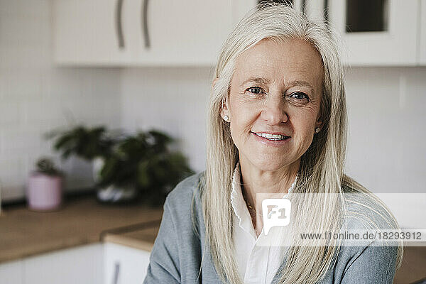Glückliche reife Frau mit grauen Haaren  die zu Hause sitzt
