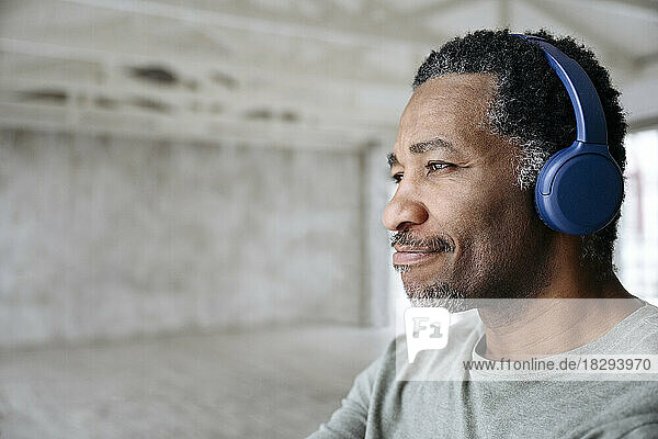 Lächelnder Mann  der zu Hause Musik über kabellose Kopfhörer hört