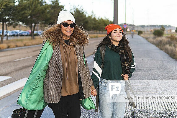 Glückliche Mutter und Tochter gehen Händchen haltend auf der Straße