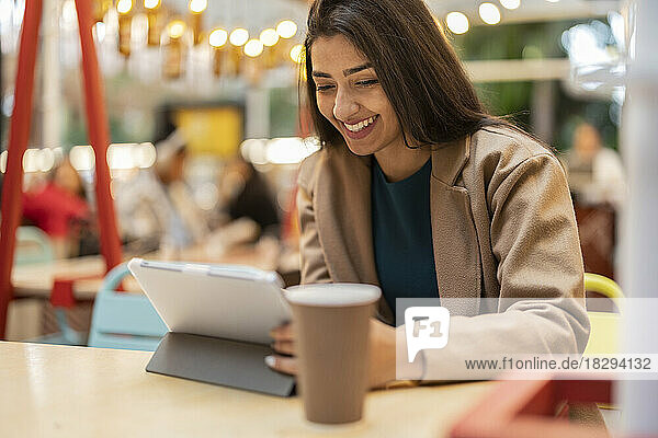 Glückliche Frau sitzt im Café und benutzt Tablet-PC