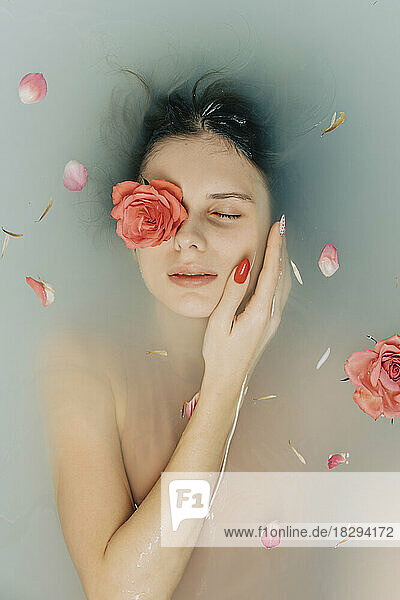 Girl taking bath with roses in bathtub
