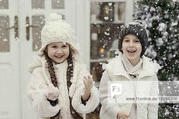 Happy brother and sister enjoying snow at front yard