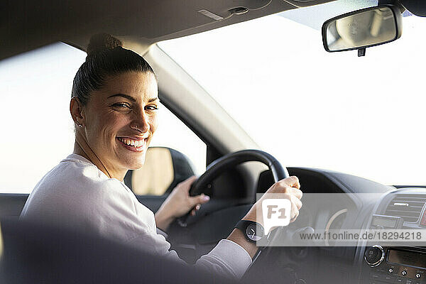 Happy young woman driving car