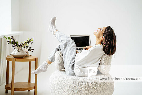 Woman resting on chair with laptop at home