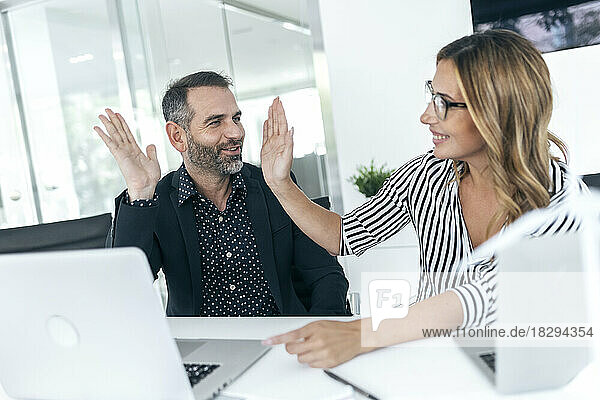 Business colleagues giving high five in office