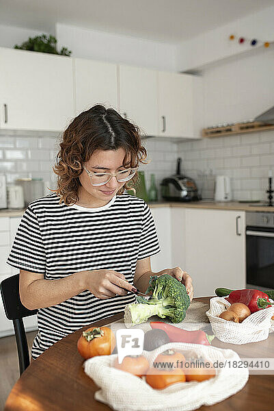 Junge Frau schneidet Gemüse in der heimischen Küche
