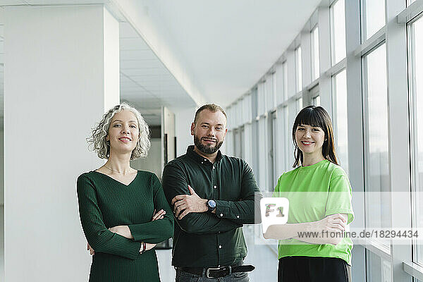 Porträt von drei selbstbewussten Geschäftsleuten in grüner Kleidung auf der Büroetage