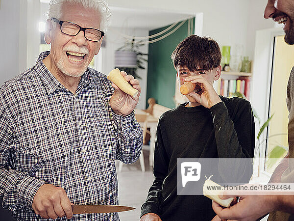 Großvater und Enkel in der Küche amüsieren sich mit Karotten