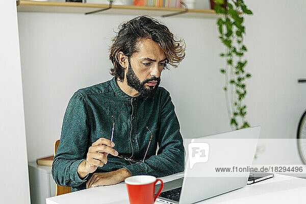 Freelancer with eyeglasses using laptop at desk