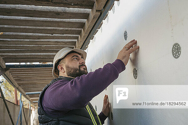 Construction worker examining polystyrene foam wall on site