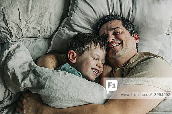 Glücklicher Vater und Sohn liegen im Schlafzimmer auf dem Bett