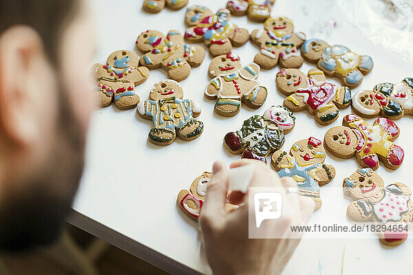Man decorating gingerbread cookies on table