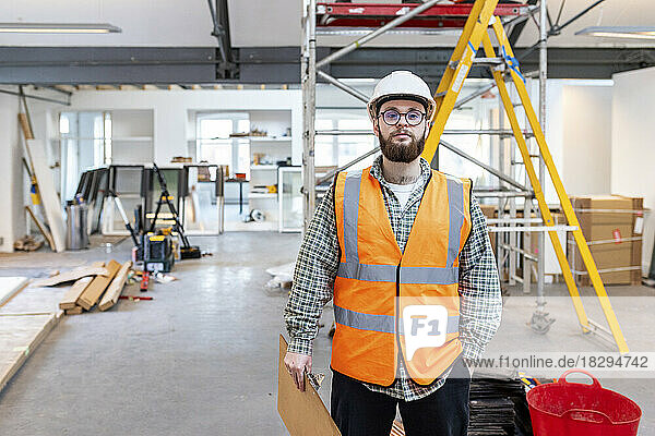 Young engineer holding clipboard standing at construction site